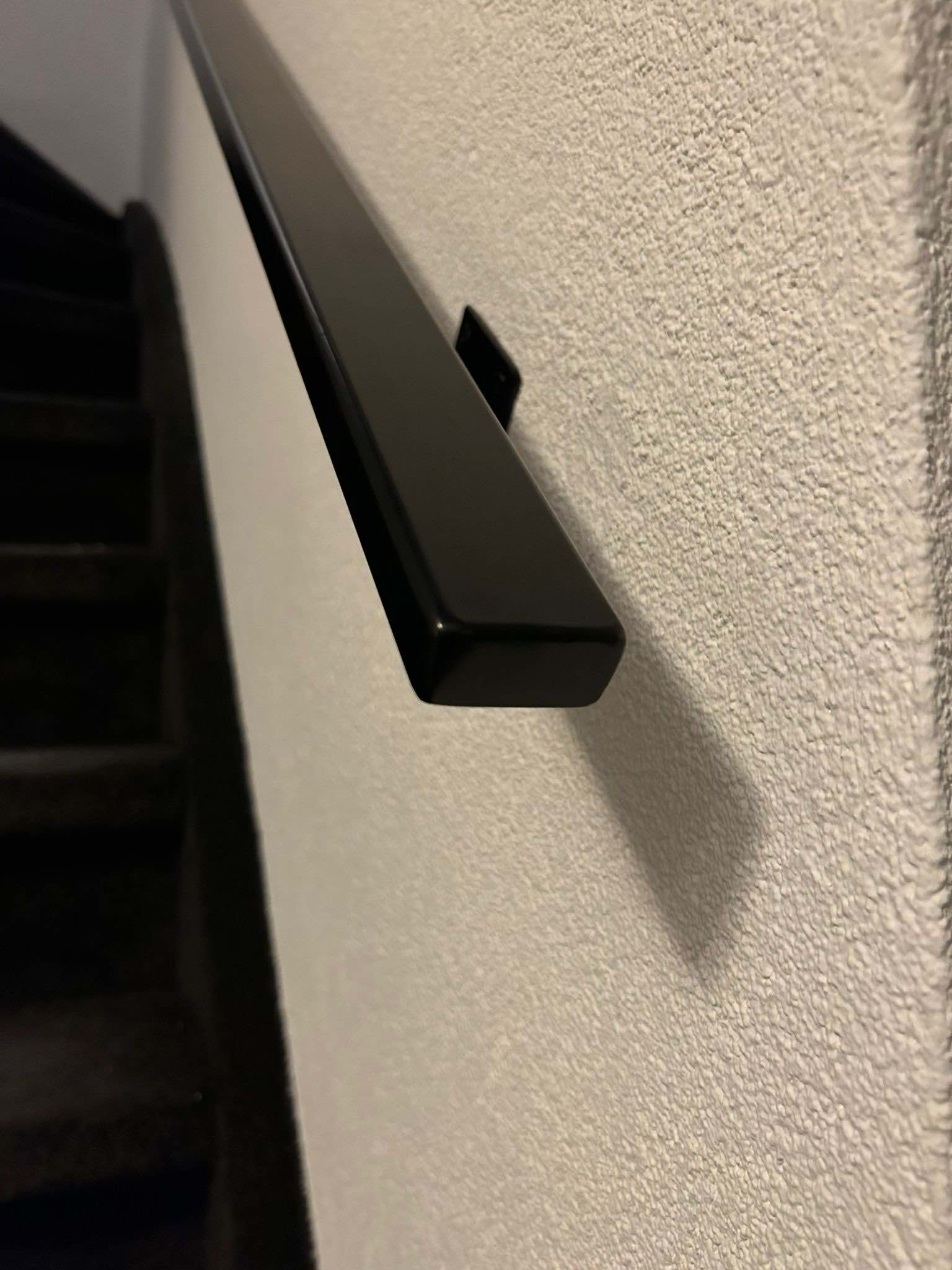 Detail van de einddop en wandbeugel van een stalen trapleuning